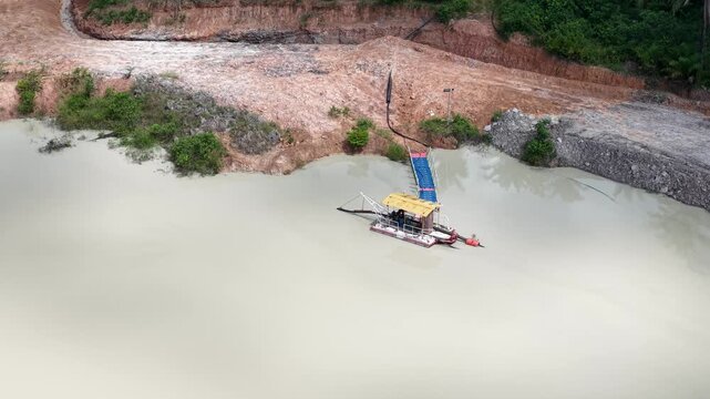 Sludge suction machine at a pit filled with sludge from mining excavation.