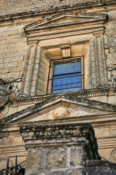 Ornate historic stone window with pediments and carved pilasters in Baeza, Spain