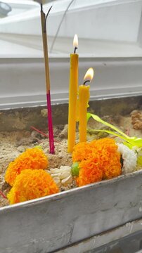 Candles, Incense Sticks and Thai Flower Garland in Joss Stick Pot in front of Chapel at the Temple, For Walk Around the Temple with a Candle at Bangkok, Thailand. 29 JUL 2026, A.M./ Slow Down Video