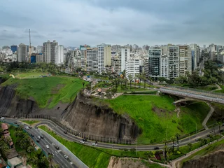 Aerial view of Love Park with its iconic sculpture, lush green gardens, and palm trees situated on the dramatic coastal cliffs of Miraflores, Peru © marchello74