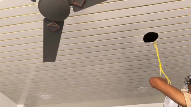 Worker installing a recessed LED ceiling light into a slatted false ceiling