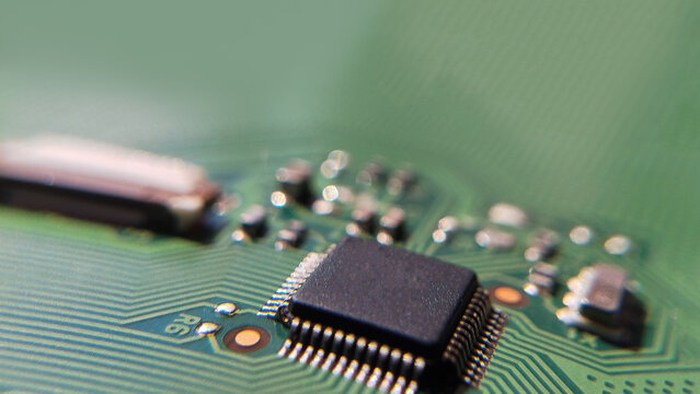 Macro view of a central square microchip processor on a green circuit board in a studio. logic controller, silicon semiconductor, computer motherboard component.