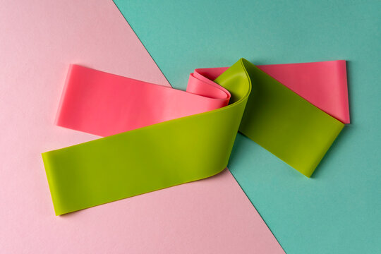 Set of elastic bands for fitness on colorful background. Pink and green fitness bands of different resistance levels.