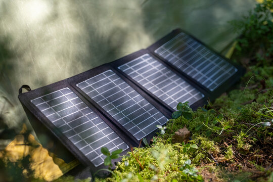 Tourist tent with solar panel and portable power station in the forest. Eco-friendly camping setup.