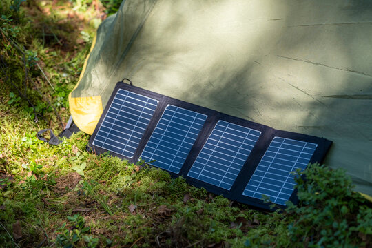 Tourist tent with solar panel and portable power station in the forest. Eco-friendly camping setup.