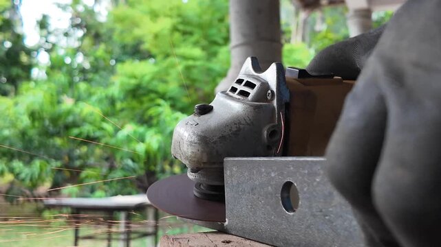 Skilled metalworker using a handheld angle grinder to smooth and shape steel during a fabrication process in a workshop.
