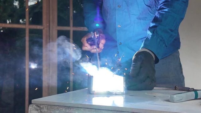 Close-up of intense electric welding sparks as a worker joins metal components during a professional fabrication process.
