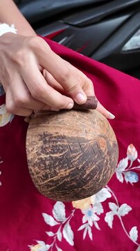 Artisan carefully polishing a coconut shell by hand to create a traditional reusable cup, showcasing sustainable craftsmanship and natural materials.