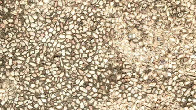 Seamless rotating loop of a natural pebble stone wash textured floor surface, featuring small gravel and rock chips embedded in concrete.