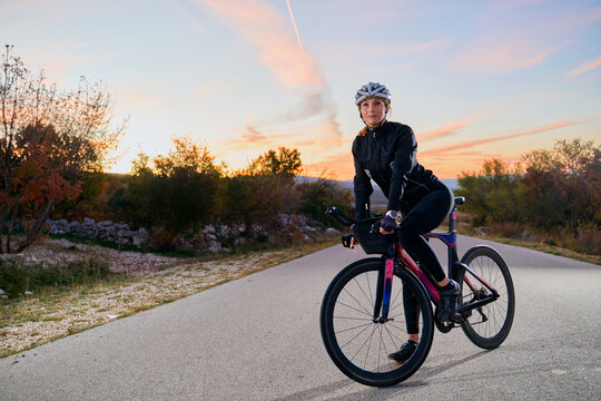 Female Cyclist On Road Bike Training at Sunset Outdoors for Fitness and Endurance