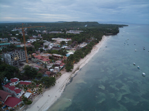 A high oblique view follows the resort-lined shore under soft fading daylight.