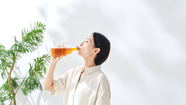 ペットボトルのお茶を飲む女性。水分補給、ウーロン茶、緑茶、紅茶、麦茶、水分補給、飲み物、ジュース