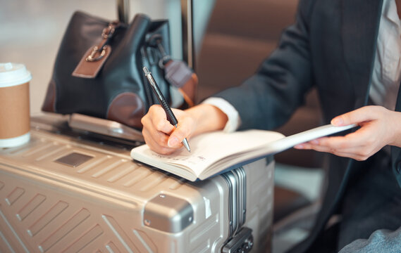 Business woman writing hand note in journal book planning for business travel at international airport terminal.