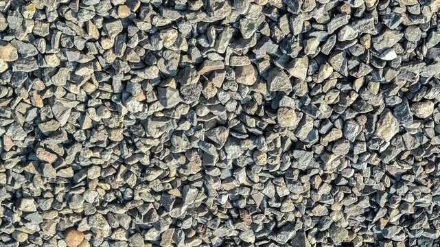 Seamless rotating loop of a natural grey crushed gravel stone aggregate surface, featuring rough rock pieces and rugged construction ballast texture.