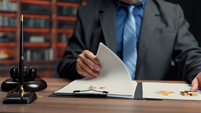 Corporate lawyer reviews settlement documents at desk, helping lawyer organize asset settlement options before another lawyer files divorce claims.