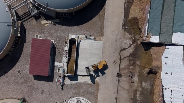 Aerial view of a tractor loading silage for biomethane production at an Italian farm, showing renewable energy production and agricultural biomass processing.
