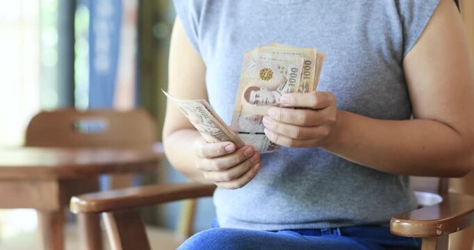 Hands counting Thai banknotes, personal finance, income, cash flow, budgeting, saving money, financial planning, and wealth management, Thai Baht, close-up