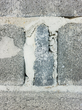 Cement mortar patch and vertical joint between gray concrete cinder blocks in wall construction