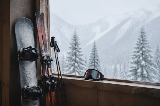 Snowboard, ski poles, and goggles on window ledge for winter sports and alpine cabin atmosphere
