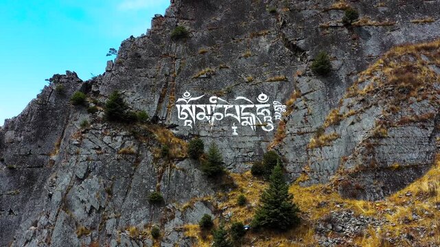 Aerial view of cliff with Tibetan scripture carving along Sichuan-Tibet highway, mountain valley landscape
