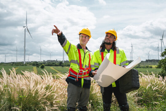 Two engineers stand in a wind farm field