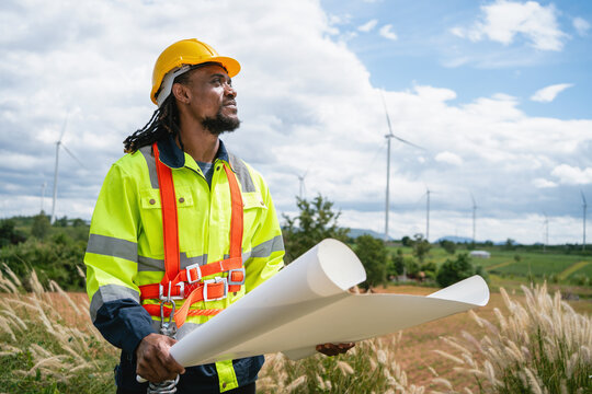 Determined worker holds blueprint under bright sky