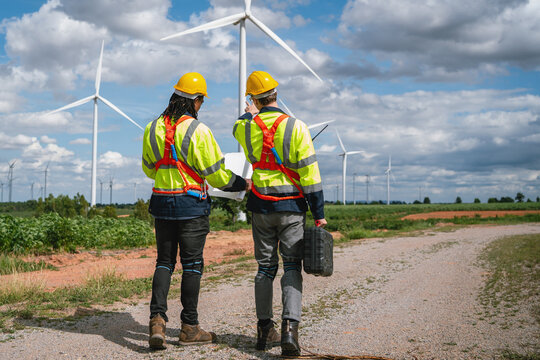 Two engineers stand on a gravel path, wearing high-visibility gear