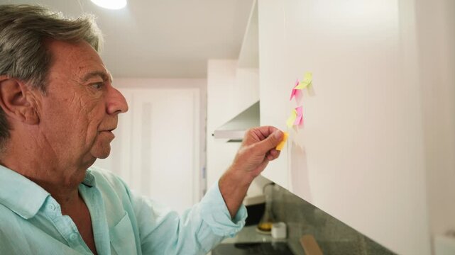 Senior man organizing tasks with sticky notes in kitchen