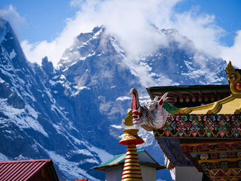 Nepalese temple roof with mythical creature, set against majestic snow-capped Himalayas, showcasing spiritual architecture and stunning mountain scenery