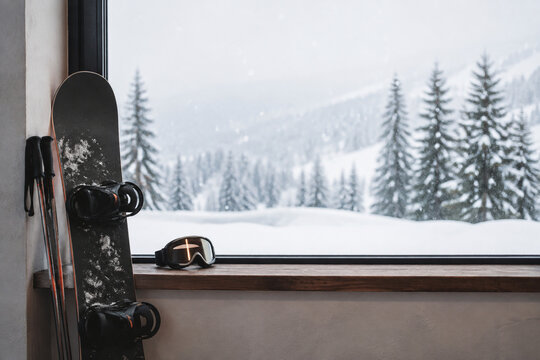 Snowboard, ski poles, and goggles on window ledge for winter sports and alpine cabin atmosphere
