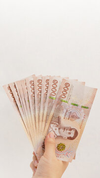 Hand holding 1000 Thai Baht banknotes on white wall background. Business and finance concept.