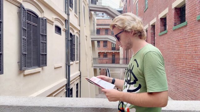 HONG KONG, CHINA &ndash; AUGUST 13, 2026: Young man with route map standing in narrow passageway between colonial buildings at Tai Kwun heritage site, former Victoria Prison.