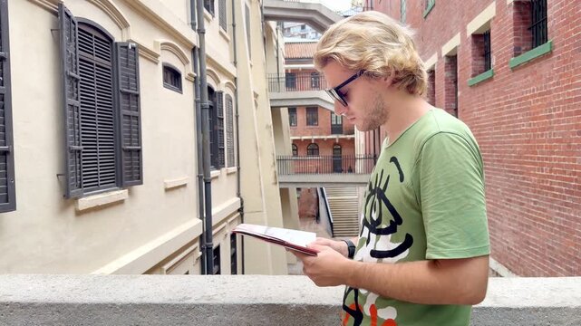 HONG KONG, CHINA &ndash; AUGUST 13, 2026: Young man with route map standing in narrow passageway between colonial buildings at Tai Kwun heritage site, former Victoria Prison.
