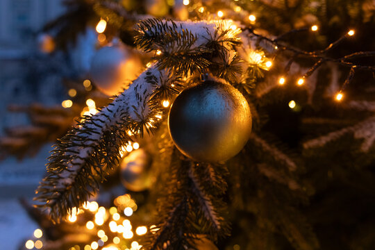 Winter holiday decorations on a tree with lights and snow in a festive setting