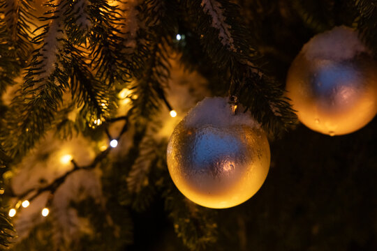 Winter holiday decorations with ornaments and lights on a snow-covered tree
