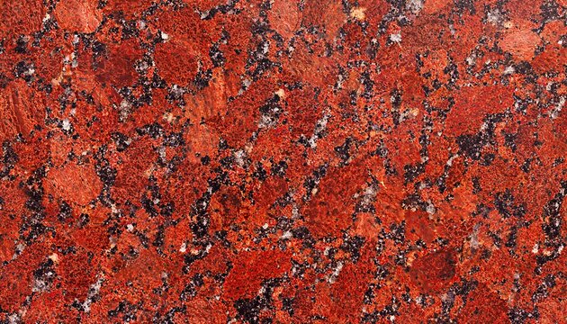 Polished red granite stone surface texture with scattered black biotite mineral speckles and white quartz crystal inclusions