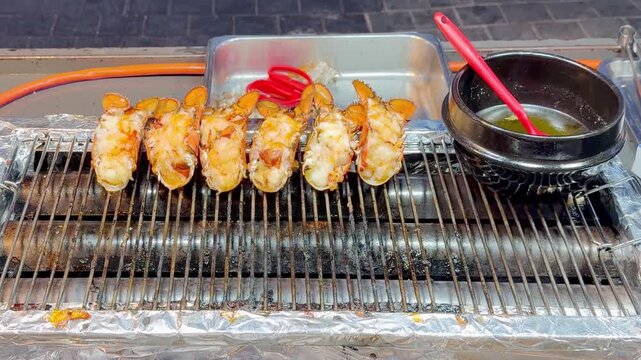Korean Street Food &ndash; Whole Lobster Grilling in Shell on Hot Griddle at Night Market Stall