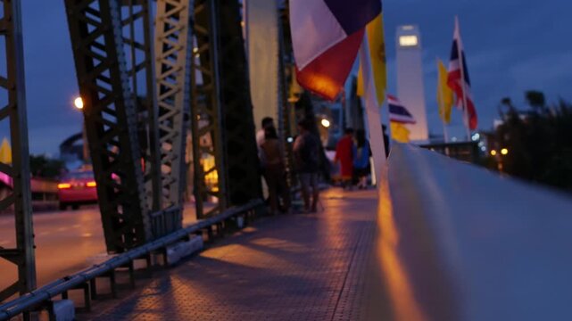 Memorial Bridge Bangkok at Dusk with Pedestrians and Traffic, Thai Flags Waving in Evening Light