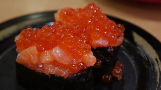 Salmon Roe Gunkan Sushi with Ikura on Black Plate, Japanese Seafood Delicacy