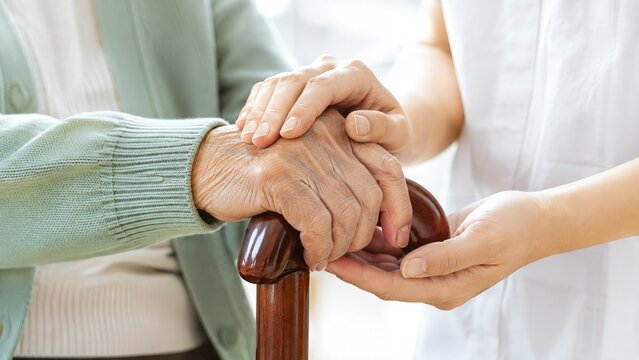 Caregiver Supporting Elderly Person with Walking Cane