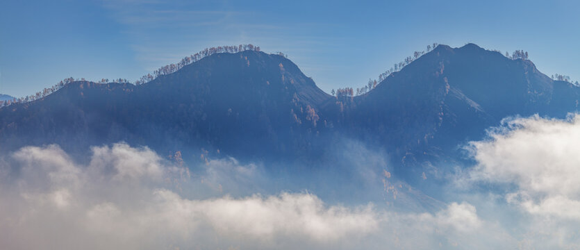 Mountains in the morning haze, peaks above the clouds, panoramic