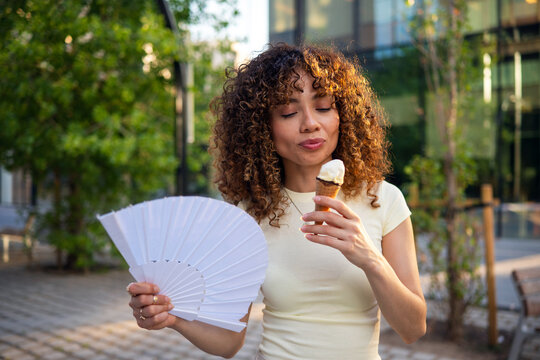 Woman enjoying ice cream and hand fan on a hot summer day
