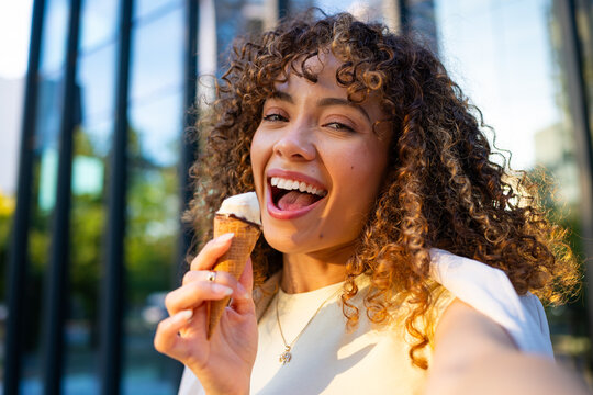 Smiling woman eating ice cream cone taking selfie