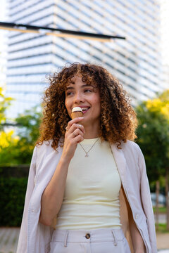 Happy young woman enjoying ice cream on city street
