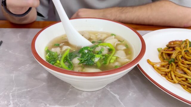 Close Up of Chinese Wontons on Restaurant Table &ndash; Traditional Dumpling Soup with Green Onions