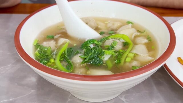 Close Up of Chinese Wontons on Restaurant Table &ndash; Traditional Dumpling Soup with Green Onions
