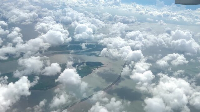 View from Airplane Window Looking Down at Clouds &ndash; Aerial Perspective of Fluffy White Clouds Over Blue Sky
