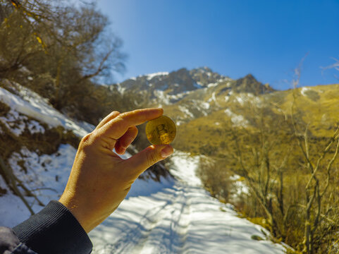 Hand Holding Cryptocurrency Coin in Snowy Kyrgyzstan Landscape