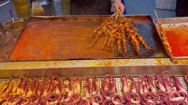 Korean Street Food &ndash; Grilling Squid and Octopus Skewers in Spicy Red Sauce at Outdoor Market Stall