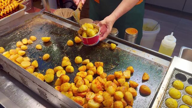 Korean Street Food &ndash; Frying Potato Slices with Red Chili Pepper on Hot Griddle at Outdoor Market